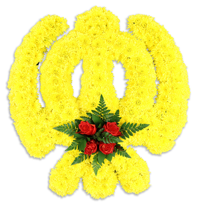A large, formal Khanda tribute occupies the image, its sacred outline rendered in a field of dense, bright yellow chrysanthemums. The petals are closely set so the circular chakkar, the upright double-edged khanda and the two crossed kirpans emerge as a single, sunlit plane with gentle relief, the texture soft yet defined under the studio light. At the exact centre, where the emblem's geometry meets, a focused cluster of deep red roses-five to six classic buds-sits like a focal medal, each rose's velvety surface contrasting with the smaller chrysanthemum heads. Lush, dark green fern fronds cradle the roses, their linear foliage providing a cool textural counterpoint and visually separating the rich red from the surrounding yellow. The background is intentionally pure white and neutral, allowing the colours to read with clarity; a subtle grey shadow beneath the work asserts its physical presence as a standing wreath or ceremonial piece used at memorials, religious services, or cultural events honouring Sikh heritage. The sensory impression is composed and respectful: a faint, sweet chrysanthemum note mingles with the deeper, emotive perfume of roses, and the overall shape projects dignity and tradition. Locally, this kind of symbolic tribute is requested by families near Canonbury Square, Newington Green and Essex Road, where community commemorations and Gurdwara services often call for florals that are faithful to emblematic detail and delivered with calm professionalism. The craftsmanship shows experienced floral construction and reverence for cultural symbolism.