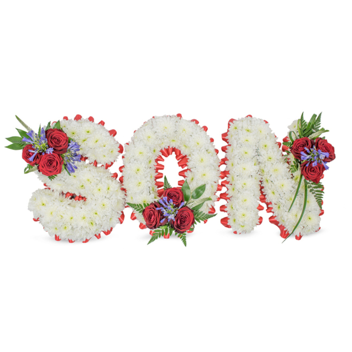 A poignant, hand-assembled tribute spelling out the word SON in prominent three-dimensional capitals, placed against a simple white background so the floristry work reads with clear dignity. Each letter is completely covered with tight clusters of pure white spray chrysanthemums, their petite blooms creating a dense, pillowy surface that suggests calm and reverence. The border of every letter is accented with a striking red satin ribbon arranged in a scalloped, pleated edge that both contrasts and sharpens the silhouette. Three refined floral groupings punctuate the composition: the S is adorned on its upper left curve with several deep crimson roses, spiky blue-purple Liatris or delphinium-like stems, and lush ferny greens; the O carries a matching cluster at its bottom centre; and the N bears a cascading assembly of roses, blue spikes and trailing foliage on its top-right stem. The combination of crisp white, passionate red and cool blue-purple produces a traditional sympathy palette that reads as love, purity and remembrance. Under soft studio light the chrysanthemums glow with a cool softness while the roses appear velvety and weighty, the blue spikes giving height and grace. This is the kind of bespoke lettering you might see placed at funeral services in Canonbury or brought by families from nearby Newington Green-a careful, tactile statement of farewell arranged with the measured skills of a seasoned local florist.