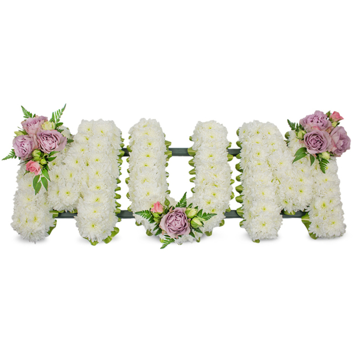 A lovingly made funeral tribute by Canonbury Flowers - the letters M-U-M are sculpted in capital form and entirely surfaced with hundreds of small, pristine white chrysanthemums, creating a uniform, cloud-like texture that reads as pure and serene against a clean white backdrop. The composition is gently punctuated by three artful clusters of pastel roses: the first cluster of lavender roses with a single pale pink bud sits on the upper left arm of the opening M; the second mirrors that palette and rests in the U's inner curve; the third, echoing the same tonal mix, crowns the upper right arm of the closing M. Each rose varies between bud and full bloom, lending velvety depth and a subtle fragrance that contrasts with the chrysanthenum's crisp freshness. Bright green foliage, including slim fern fronds and lighter green leaflets, is interspersed to add texture and a natural frame, while a dark green structural base - likely ribboned or mossed - shows faintly beneath the blooms as a stabilising outline. The lighting is soft and contemplative, as one might see in a chapel near Canonbury Square or along New River Walk, where the tribute would sit as a calm focal point. This piece speaks of dignified remembrance and maternal love, a traditional and personal sympathy tribute suitable for a mother's funeral, wake, or graveside service, and can be arranged for delivery across Canonbury and neighbouring Islington.