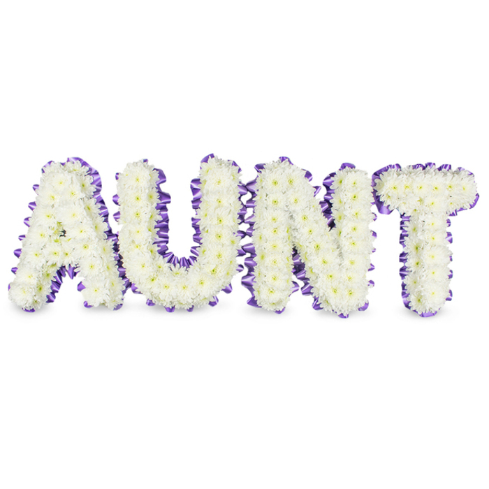 A meticulously arranged sympathy piece spells the word 'AUNT' in bold, gallery-sized letters, each formed by a dense carpet of small, immaculate white spray chrysanthemums. The multitude of tiny petals creates a soft, tactile surface that reads as both delicate and enduring; flecks of pale yellow at the flower centres add a subtle, natural warmth that prevents the composition from feeling austere. Each letter is outlined in a deep purple satin ribbon, carefully ruffled and pleated to provide a textured frame that accentuates the letter shapes and adds a note of refined contrast against the white blooms. Soft grey shadows beneath the letters emphasise their relief from the white ground, suggesting a solid, tasteful construction that will hold up during viewing at a service. The scent is mild and green, like washed linen, reinforcing the arrangement's serene mood rather than dominating it. As an Islington-made tribute, this piece carries the quiet authority of a florist who understands local customs-from small chapel services near New River Walk to larger gatherings on Upper Street. The white chrysanthemums are chosen for their longevity and association with remembrance, while the purple edging introduces a dignified, almost poetic cadence to the composition. Placed near Canonbury Square or delivered along Essex Road, the tribute functions both as a clear, personalised message and as a comforting focal point for family and friends to gather around in memory of a treasured aunt.
