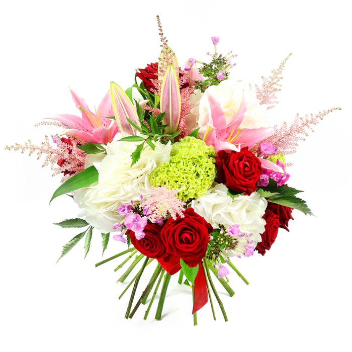 This image shows a luxurious, hand-tied floral bouquet photographed against an immaculate white background, making every shade and curve of the arrangement easy to visualise. Dominating the composition are velvety crimson roses, each bloom fully formed and tightly layered, embodying deep romance and timeless elegance. Interlaced with them are several pink lilies, some dramatically open with wide, silky petals revealing their stamens, others still tall and slender in bud, promising a slow, graceful unfolding. Around these focal flowers, generous clusters of soft white blooms-resembling voluminous carnations or garden-style roses-form a plush, cloud-like foundation that gives the bouquet a grand, almost couture presence. At the centre, a compact globe of vivid lime green dianthus, often known as a Green Trick carnation, offers a playful jolt of colour and a fascinating, fringed texture that draws the gaze inward. Rising above the main mass are delicate, feathery sprigs of light pink astilbe, bringing a sense of movement and airy romance, as if caught in a gentle breeze over Canonbury Square. Small accents of fuchsia and lavender flowers are tucked amongst the larger heads, adding depth and nuance, like scattered confetti. Deep green foliage peeks out from beneath and between the blossoms, supporting the structure while enriching the palette with natural contrast. At the base, the stems are gathered cleanly and tied with a slender, dark red satin ribbon, underscoring the bouquet's hand-crafted character and readiness for gifting. Ideal for celebrations, anniversaries, or thoughtful same-day delivery across Canonbury, this arrangement conveys joy, passion, and considered design in every carefully placed stem.