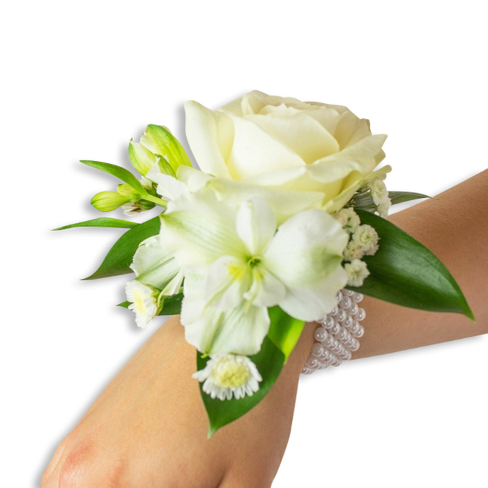 Seen from a slightly elevated angle against a clean white backdrop, this wrist corsage reads as an intimate, handcrafted accent for a Canonbury celebration. At the centre is a perfectly formed creamy white rose whose soft, layered petals unfurl with a satin glow. Below it, to the left, a larger trumpet-shaped white flower - likely an Alstroemeria (Peruvian lily) - showcases a subtle lime-green throat that deepens the composition and draws the eye inward. Interspersed between the main blooms are tiny sprays of Gypsophila (Baby's Breath) and several unopened green buds, their compact forms promising a gentle change as the evening progresses. Close to the wrist, a little cluster of daisy-like white florets with sunny yellow centres adds a note of cheer and contrast. Rich, waxy deep-green leaves frame the ensemble, their smooth surfaces reflecting soft studio light and giving the corsage an organically full silhouette. The floral cluster is mounted on a chic multi-strand elastic bracelet of lustrous white pearls; the pearls sit cool and round on the skin, lending a timeless, bridal quality. As a local florist serving Canonbury and nearby streets like Essex Road, New River Walk and Upper Street, Canonbury Flowers crafts pieces like this for weddings, proms and formal events - always using fresh blooms arranged with care. The overall effect is one of poised elegance: tactile, fragrant, and ideal for a neighbourhood celebration or a riverside photo in Canonbury Square.