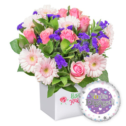 This joyful bouquet, imagined by Canonbury Flowers, arrives in a clean white square box and radiates warm celebration. Soft pink roses mingle with pastel pink gerbera daisies, their petals unfurling in creamy spirals and hinting at romance, while delicate clusters of deep purple filler flowers punctuate the arrangement with surprising color. A generous plume of green foliage provides a fresh, natural backdrop, giving the bouquet a garden-fresh feel. A round foil balloon, perched at the bottom right, features a lavender surface and the message You're Engaged! in silver, with the O styled as a golden engagement ring and a white border adorned with small hearts and silver stars. A small red rose emblem decorates the front of the white box, signaling craftsmanship without overpowering the composition. This piece is a thoughtful, heartwarming gift for someone in Canonbury or nearby Islington neighbourhoods, perfect for celebrating a proposal or engagement milestone. Delivered with care, it's available for same-day delivery across Canonbury, Upper Street, and Essex Road, bringing bright happiness to homes from Canonbury Square to New North Road.