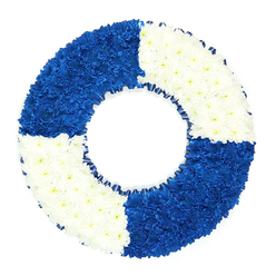 Set against a clean, white studio backdrop, this maritime lifebuoy wreath appears almost to float, its colours as clear and defined as a navigation marker on a bright day. The circular tribute is meticulously composed from hundreds of small chrysanthemum-like flowers, each bloom tucked closely into the next until no gaps remain, forming a plush, velvety ring of petals. The design is quartered with purpose: the top left and bottom right panels are rich royal blue, intense and saturated, while the top right and bottom left glow in pure white. The blues suggest deep, open water, calm yet powerful, while the whites bring balance, hinting at foam-tipped waves and the serenity of a clear sky over Canonbury's rooftops. Around the inner opening runs a slim frill of dark blue ribbon, looped and pleated in gentle folds to echo the circular form, framing the hollow centre and emphasising the classic lifebuoy silhouette. There are no extra adornments, no foliage or lettering; instead, the impact comes from the disciplined colour blocking and the flawless curvature of the ring. As a sympathy or funeral tribute, it carries the quiet symbolism of support, safety, and guidance-ideal for remembering someone connected to maritime work, canal boating near Angel, or simply a person known as a steady, dependable lifesaver in their family. Crafted with the precision of a skilled local florist, it would be suitable for dignified delivery to services throughout Canonbury, Highbury, and surrounding North London, offering a respectful, sea-inspired final farewell.
