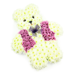 A floral teddy bear tribute is captured in clear, even light, its gentle features fashioned entirely from fresh blooms that seem to soften the stillness of the white background. The body is densely covered with creamy white chrysanthemums, each small flower overlapping the next to create the rounded head, plump cheeks, neat ears, and cuddly paws of a classic teddy. The petals look feathery yet structured, as though they might spring back to the touch, echoing the feel of a well-loved soft toy. The bear's expression is created with care: two small, dark eyes sit close together, giving a look of steady watchfulness, while a tiny black triangular nose anchors the centre of the face. A hint of a smile is suggested below, delicately curved and subtle, conveying reassurance and peace. Draped across the front is a vivid vest of mauve and deep pink flowers, likely hydrangea or rich-toned chrysanthemums, forming a playful waistcoat shape that introduces depth and contrast. At the neckline rests a neatly tied purple net bow, its gauzy loops and tails adding a whimsical flourish against the structured petals. The arrangement feels thoughtfully balanced, with every edge, curve, and colour transition clearly visible against the bright, uncluttered backdrop. As a tribute designed for quiet moments of remembrance in Canonbury and nearby Islington streets, it could rest gently at a child's farewell, a memorial in a local church off Upper Street, or a private gathering at home. This bear speaks softly of innocence, protection, and love, a floral companion that holds space for grief while offering the comfort of cherished childhood memories.