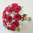 A carefully crafted bouquet of red roses and white gypsophila is shown in a gentle wash of daylight, the arrangement looking as if it has just been set down in a calm Canonbury living room before the guests arrive. The roses sit in a rounded dome, each bloom lush and velvety, with petals that curl inwards like folded silk, shaded in tones of crimson and garnet that suggest romance, loyalty, and timeless devotion. Between the roses, sprays of baby's breath spread out like soft white mist, their many tiny petals catching the light and giving the bouquet a dreamy, ethereal quality. A few polished green leaves encircle the base, deepening the colour contrast and echoing the plane trees that line the streets around Canonbury station. The stems are gathered tightly and bound with an elegant ribbon studded with small pearls, the handle smooth and secure in the hand, created with the confidence of a florist used to preparing wedding flowers for local ceremonies and receptions. The atmosphere of the arrangement is both intimate and celebratory, like the quiet moments before vows are spoken in a nearby Islington registry office. Though the image is still, you can almost sense the soft, sweet fragrance drifting upwards, a reminder of fresh, early-morning deliveries and bouquets being prepared for same-day celebrations across Canonbury, Highbury, and neighbouring Angel. This bouquet feels ideal for bridal parties, anniversary surprises, or heartfelt declarations, wherever enduring love is being honoured.