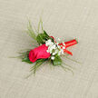 This boutonnière presents a single, vivid magenta-pink rose as its focal point, the flower's plush petals arranged in a compact rosette that appears both strong and delicate. Behind it, firm green foliage and slim, reed-like leaves arc calmly outwards, adding height and movement while framing the rose in a natural, almost sculptural way. Nestled alongside the central bloom, clusters of white gypsophila-often called baby's breath-float like tiny stars, their miniature blossoms dusting the design with softness and a whisper of vintage romance. The stem is wrapped with meticulous precision in a bright red satin ribbon, wound tightly in smooth circuits that gleam just enough to suggest festivity without overwhelming the gentle colours above. The background is a muted fabric, slightly textured, which allows the rich pink, clear white, and deep green to stand out with clarity. The overall mood is intimate and celebratory, ideal for a groom, best man, or special guest walking the leafy streets of Canonbury toward a ceremony, perhaps near Canonbury Square or a hidden Islington venue. The imagined scent is that of a freshly cut rose-light, sweet, and green-edged-carried subtly with each movement. To me, the piece reflects the balance we aim for in Canonbury: contemporary yet timeless, a single rose boutonnière that speaks of care, craftsmanship, and the quiet thrill of an important day shared with loved ones.