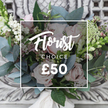 A hand-tied bouquet captured on an antique cream console, the arrangement radiates soft, garden-picked romance. Prominent blush-pink roses with velvety, unfurling petals form the heart of the design, their pale warmth contrasted by clusters of bright white berries and tiny, airy white filler blooms that could be waxflower or astrantia. Silvery-blue eucalyptus leaves spill through the bouquet, their rounded shapes and muted tones giving a cool, aromatic backdrop that you can almost smell in the image. Hints of deeper pink and burgundy buds add depth, while taller, slender green-and-white spikes peek from the sides to introduce vertical rhythm. The stems are gathered with a cream satin ribbon, the knot visible beneath the flowers, reinforcing the hand-tied, bespoke feel. The bouquet rests against a softly blurred carved plaster or stone surround, the pale, ornate background lending an elegant, timeless setting to the fresh florals. Soft daylight falls across the petals, producing gentle highlights and a calm, refined mood-a perfect gift for a birthday, an understated anniversary, or to welcome a new home on a quiet Canonbury morning. Overlaying the composition is a simple white rectangular frame containing text: a flowing script reading 'Florist' above the word 'CHOICE' and a clear price displayed as '?50', indicating a curated florist's selection. The image invites touch as much as sight: the velvet of the roses, the prickle of greenery, the cool sheen of eucalyptus. It reads as a carefully considered seasonal choice from a local Canonbury florist, ideal for delivery to nearby streets like Canonbury Square, Essex Road, or Upper Street when you want to send something both elegant and naturally fresh.